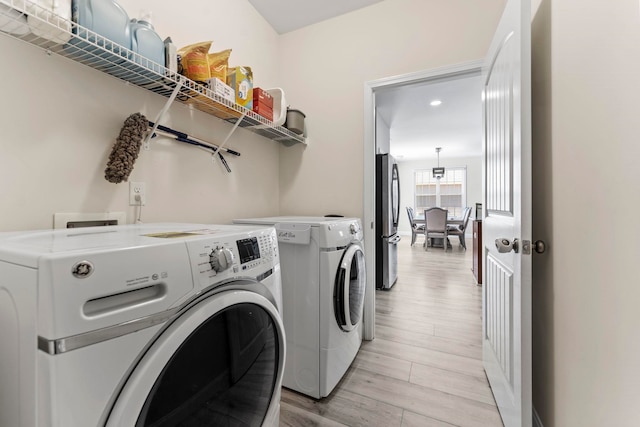 laundry area featuring laundry area, washer and clothes dryer, and light wood-type flooring