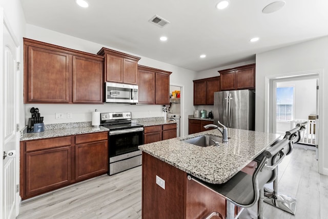 kitchen with appliances with stainless steel finishes, visible vents, a sink, and light wood-style flooring