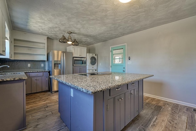 kitchen featuring stacked washer and dryer, stainless steel appliances, dark wood-style flooring, a sink, and open shelves