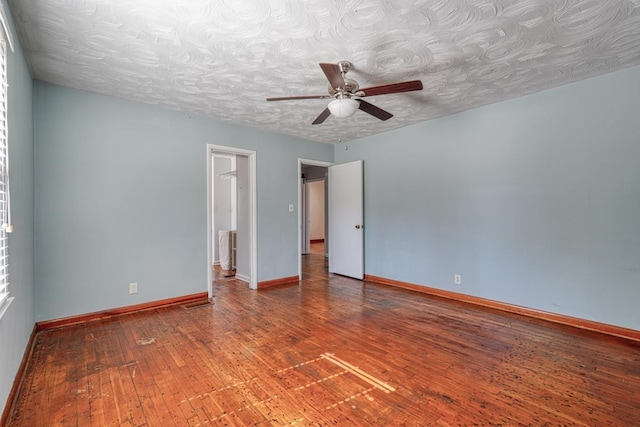 spare room with a textured ceiling, wood-type flooring, a ceiling fan, and baseboards