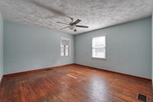 spare room with hardwood / wood-style flooring, baseboards, and visible vents