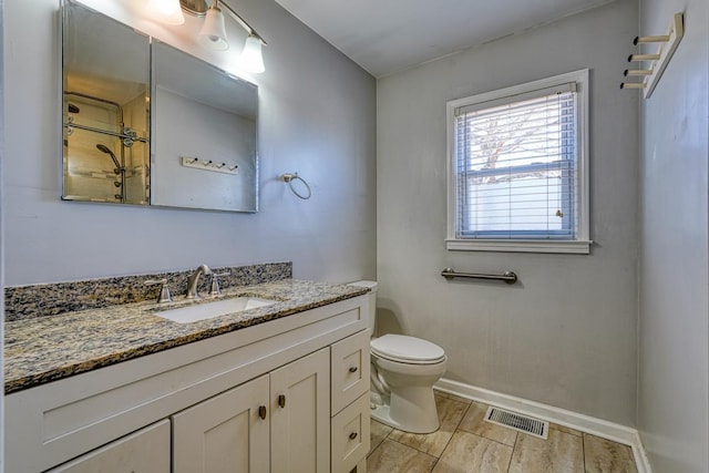 bathroom featuring toilet, vanity, visible vents, baseboards, and wood tiled floor