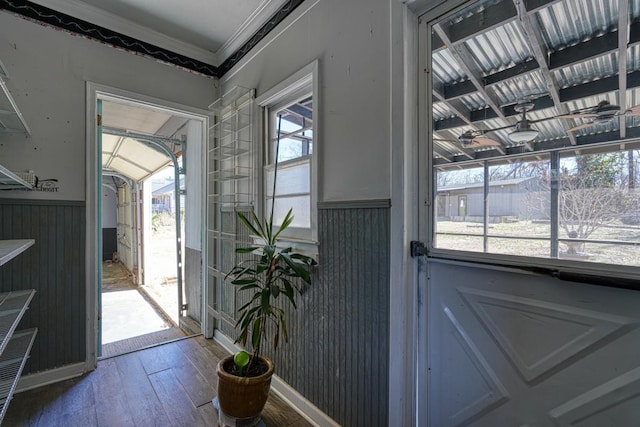 doorway with a wainscoted wall, hardwood / wood-style floors, and crown molding