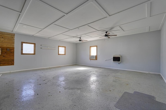 unfurnished room featuring finished concrete flooring, heating unit, a ceiling fan, cooling unit, and baseboards