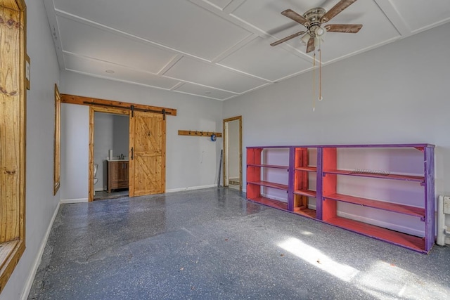 unfurnished room with speckled floor, a barn door, a ceiling fan, and baseboards