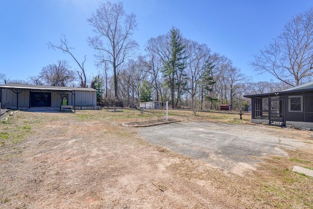 view of yard with driveway, a sunroom, a pole building, and an outdoor structure