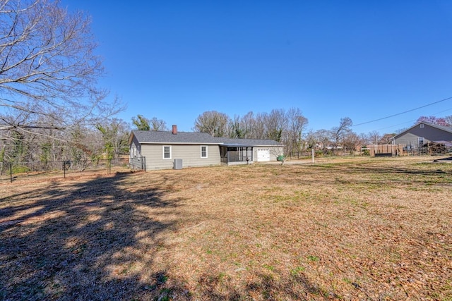 rear view of property featuring an attached garage, fence, and a lawn