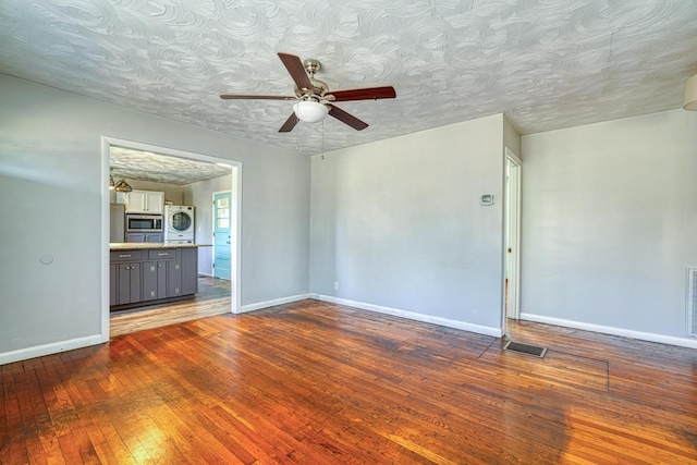 unfurnished room featuring wood-type flooring, a textured ceiling, visible vents, and baseboards