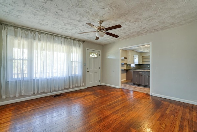 interior space with ceiling fan, dark wood-type flooring, visible vents, and baseboards