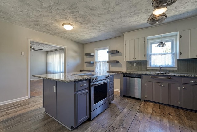 kitchen featuring stainless steel appliances, wood finished floors, open shelves, and light stone counters