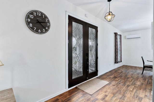 foyer featuring french doors, a wall unit AC, wood finished floors, and baseboards