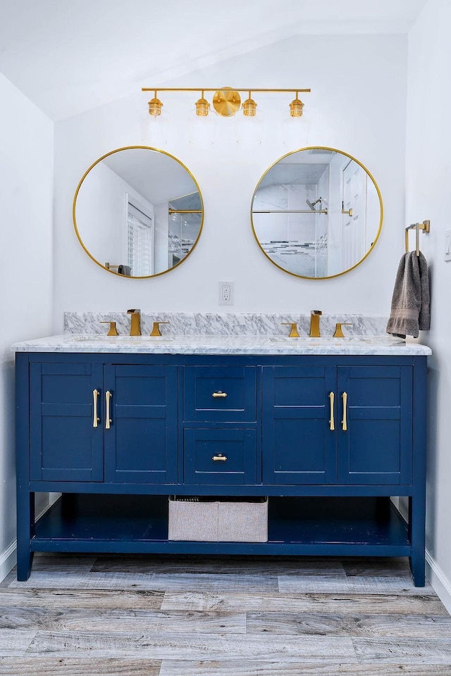 full bathroom featuring double vanity, wood finished floors, a sink, and baseboards