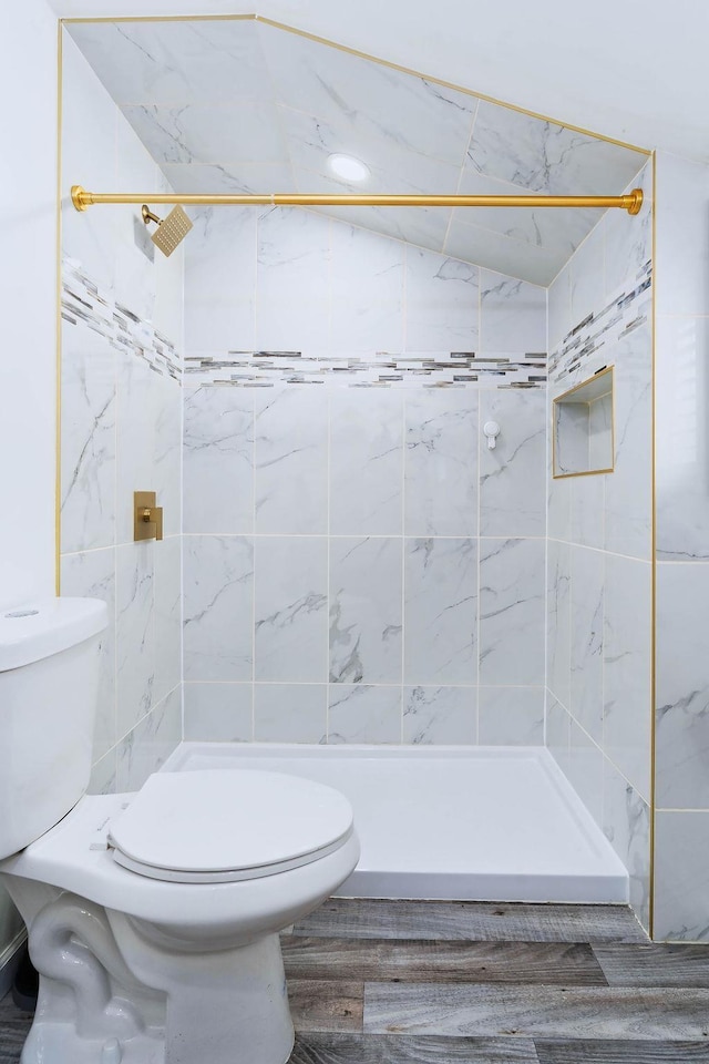 bathroom with a stall shower, vaulted ceiling, tile walls, and toilet