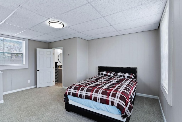 carpeted bedroom featuring a paneled ceiling and baseboards
