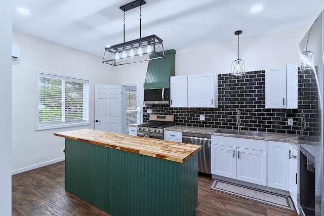 kitchen with white cabinetry, wood counters, appliances with stainless steel finishes, and a sink