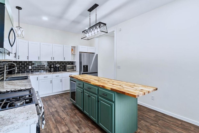 kitchen featuring tasteful backsplash, butcher block countertops, stainless steel appliances, white cabinetry, and a sink