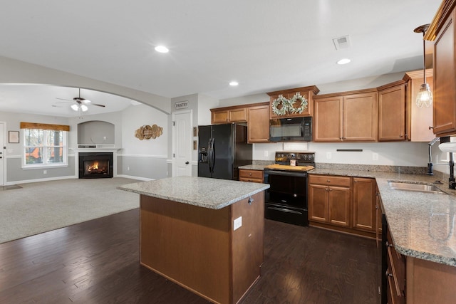 kitchen with brown cabinetry, a center island, a sink, and black appliances