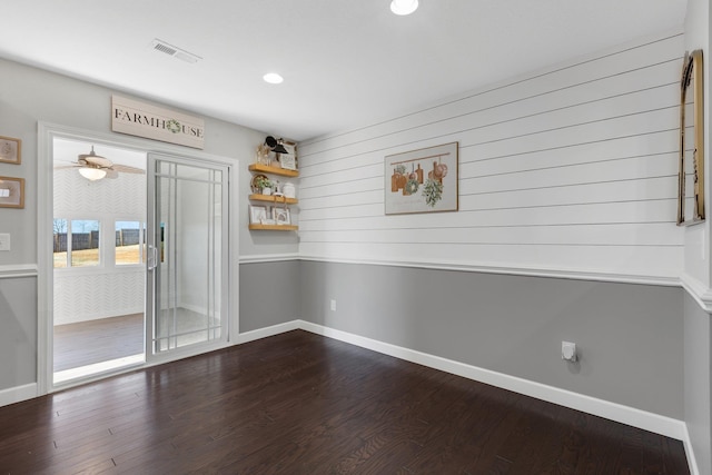 empty room with baseboards, visible vents, and dark wood-type flooring