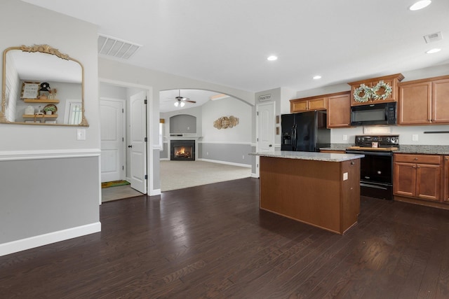 kitchen featuring a center island, visible vents, a lit fireplace, and black appliances