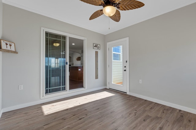 empty room featuring crown molding, baseboards, and wood finished floors