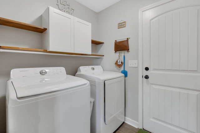 washroom featuring separate washer and dryer, cabinet space, and baseboards