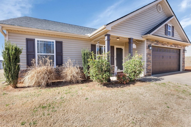 view of front of house featuring driveway, stone siding, a garage, and roof with shingles