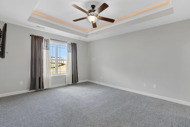 spare room featuring ornamental molding, a tray ceiling, carpet, and baseboards