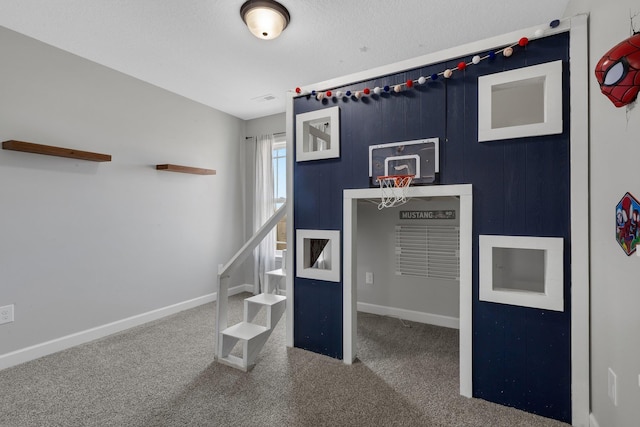 interior space with a textured ceiling, carpet floors, and baseboards