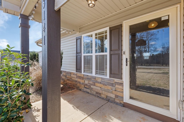 property entrance featuring covered porch and stone siding