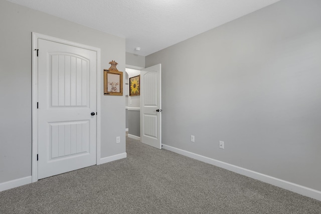 unfurnished bedroom with carpet floors, a textured ceiling, and baseboards