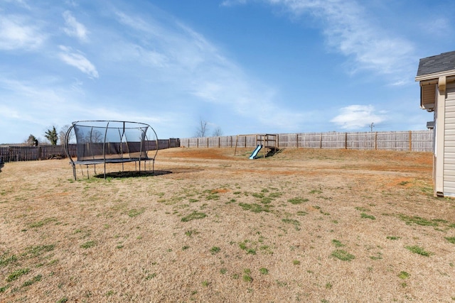 view of yard with a fenced backyard, a trampoline, and a playground