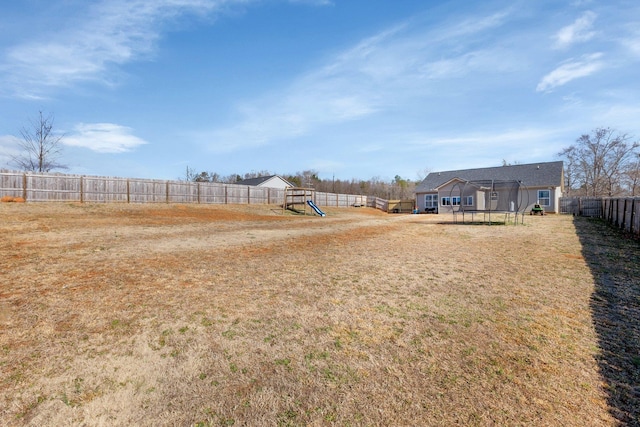 view of yard featuring a fenced backyard, a trampoline, and a playground