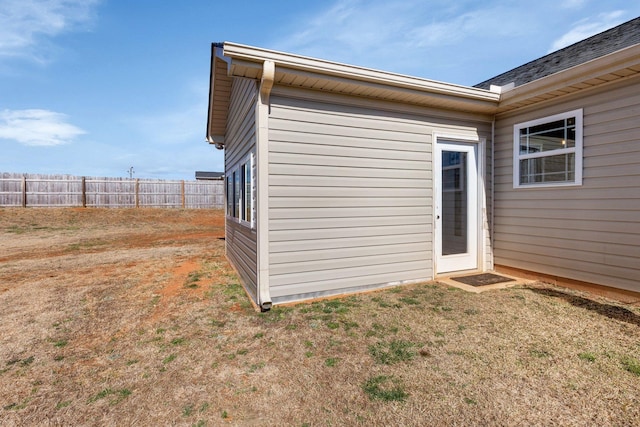 view of side of home with a lawn and fence