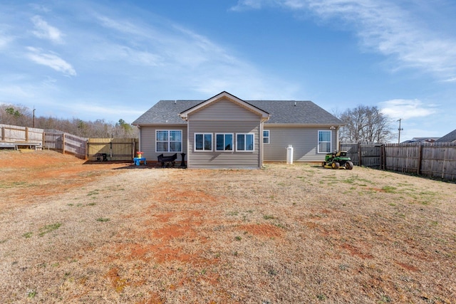 rear view of house featuring a fenced backyard and a yard