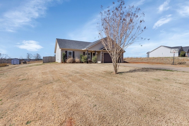 ranch-style home with an attached garage, a storage shed, a front yard, fence, and driveway