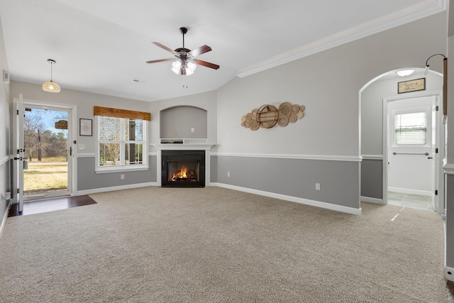 unfurnished living room featuring a warm lit fireplace, carpet, baseboards, and a healthy amount of sunlight