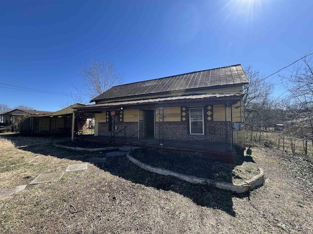 view of front facade with metal roof, a porch, and brick siding