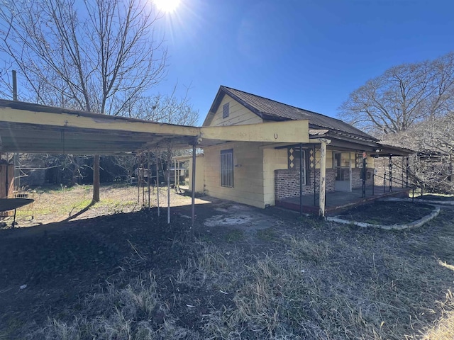 view of side of property featuring a patio area, concrete block siding, and metal roof