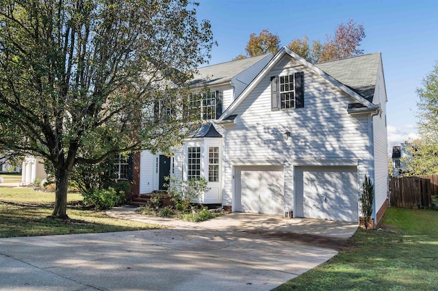 traditional-style home with driveway, a front yard, an attached garage, and fence
