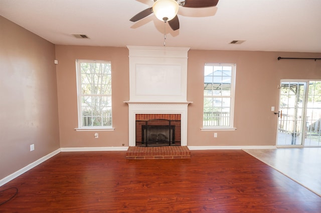 unfurnished living room featuring wood finished floors, plenty of natural light, ceiling fan, and visible vents