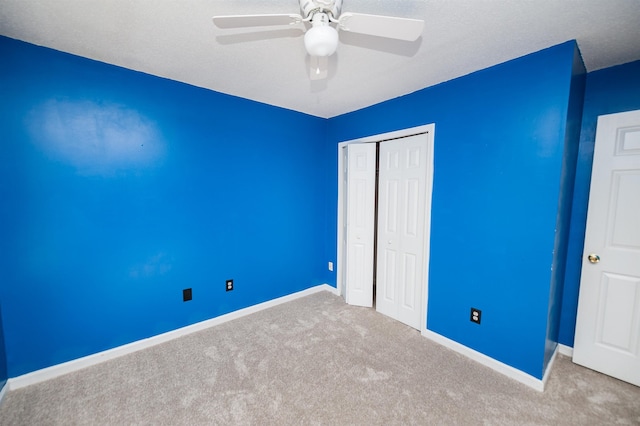 unfurnished bedroom featuring carpet floors, baseboards, a closet, and ceiling fan