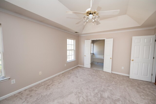 unfurnished bedroom with carpet flooring, baseboards, ornamental molding, a ceiling fan, and a tray ceiling