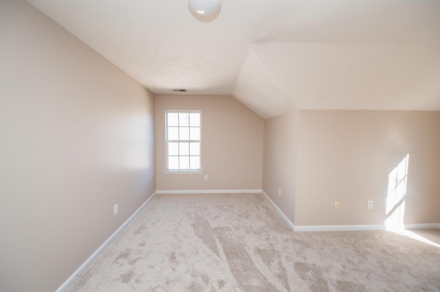 additional living space featuring carpet floors, baseboards, vaulted ceiling, and visible vents