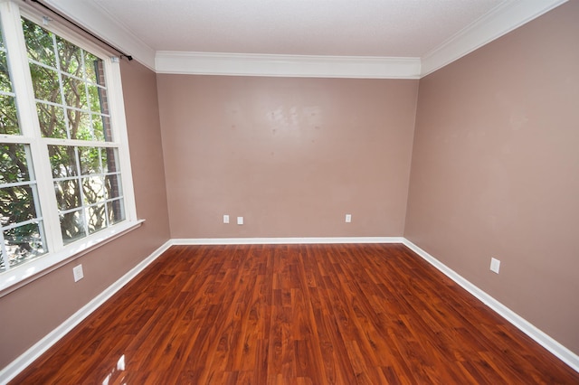 spare room featuring baseboards, ornamental molding, and dark wood finished floors