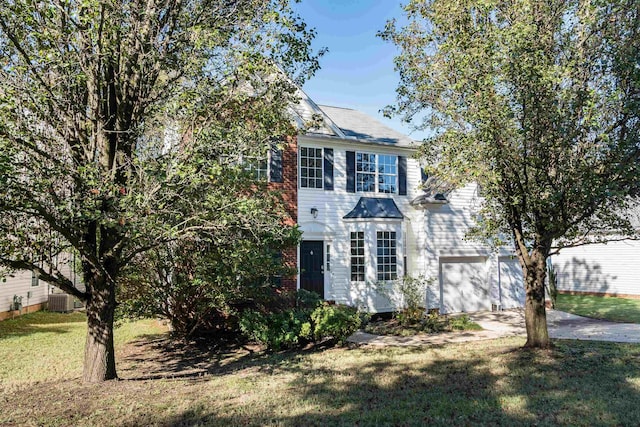 colonial inspired home with cooling unit, concrete driveway, an attached garage, a front yard, and brick siding