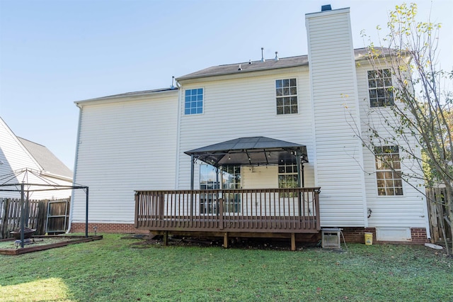 rear view of property featuring fence, a chimney, a gazebo, a deck, and a lawn