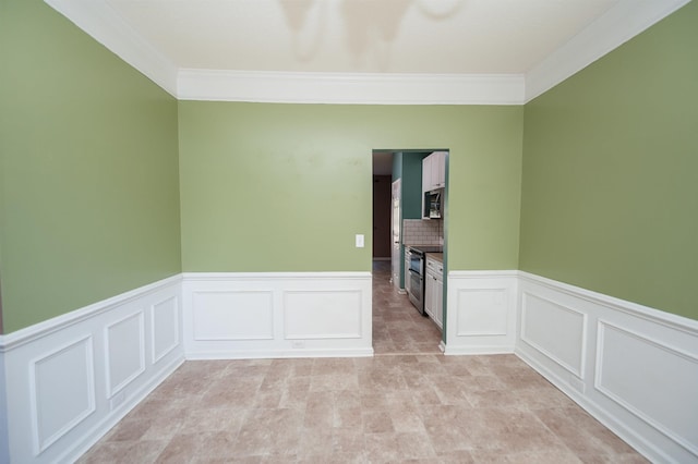 empty room featuring crown molding and wainscoting