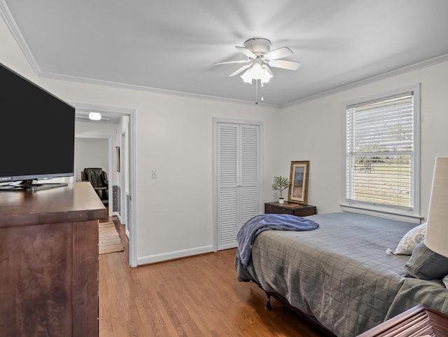 bedroom featuring light wood-type flooring, a closet, baseboards, and crown molding