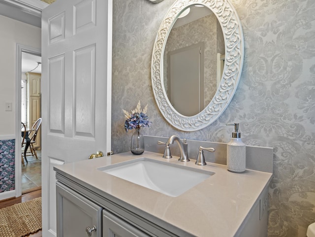 bathroom featuring wood finished floors, vanity, and wallpapered walls