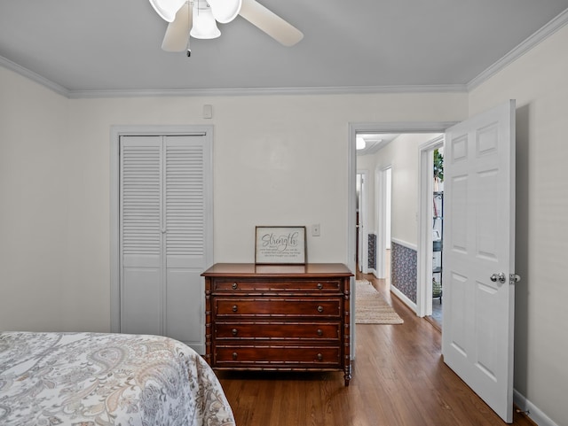 bedroom with ornamental molding, a closet, dark wood finished floors, and a ceiling fan